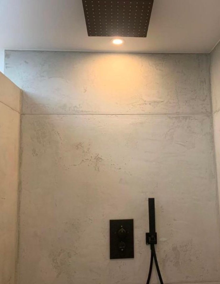Mikrozement Bad Minimalist Duschbereich mit grauen Wänden und Deckenstrahler.