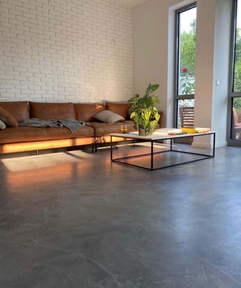 Helles, modernes Loft mit großen Fenstern, minimalistische Möbel und einem Mikrozement Boden im Industriell Design