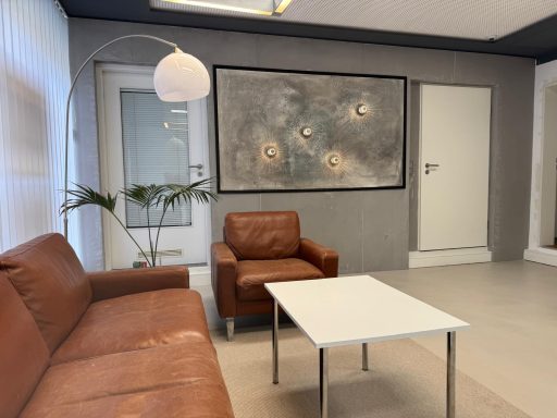 Sitzbereich mit braunen Ledermöbeln, einem Tisch und modernen Wandkunst.