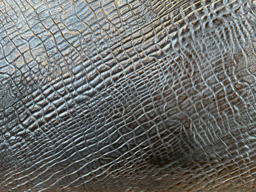 Strukturierte Oberfläche in Grautönen mit einem schlangenartigen Muster.