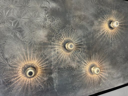 Wand mit vier dekorativen, strahlenden Leuchten in verschiedenen Anordnungen.