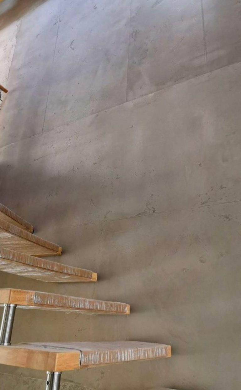 Mikrozement Wand Bodenansicht mit glattem, grauem Beton und Holzgeländer.