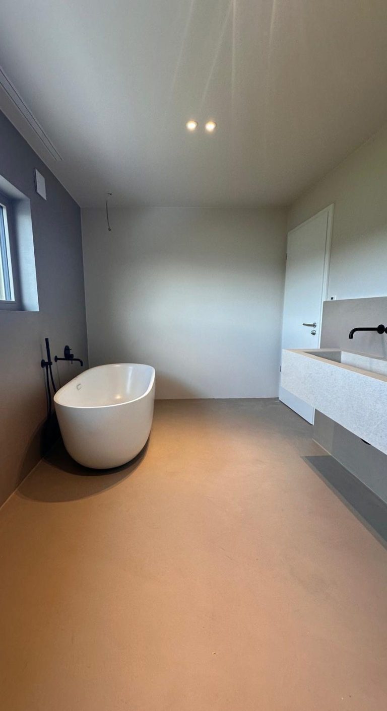 Mikrozement Wand Modernes Badezimmer mit Mikrozement, freistehender Badewanne und einfacher Waschbeckenanlage.