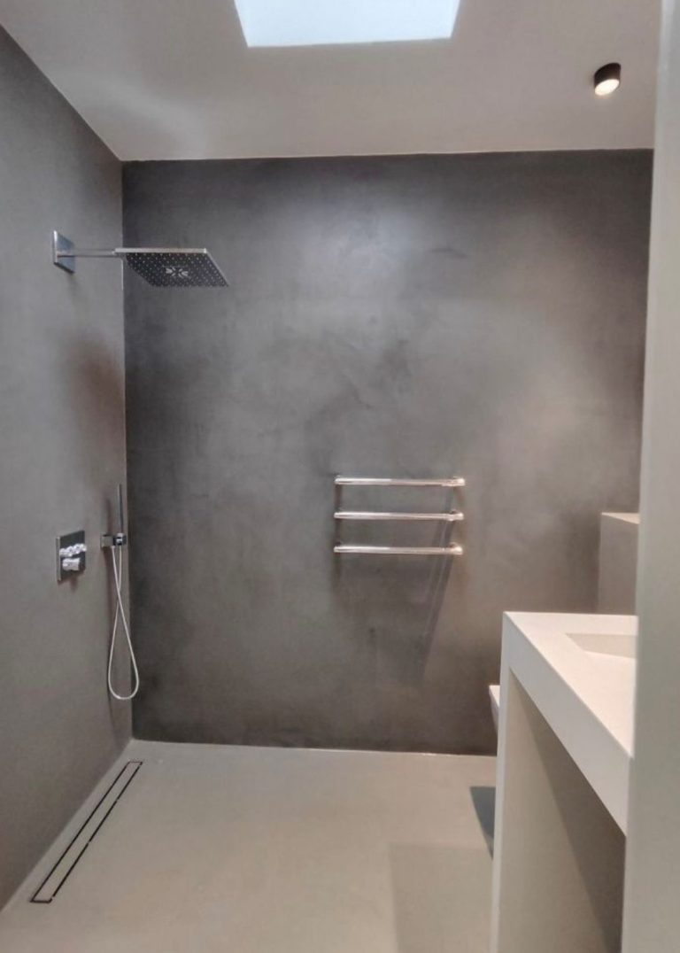 Mikrozement Bad Moderne Badezimmeransicht mit grauen Wänden, Dusche und handtuchhalter.