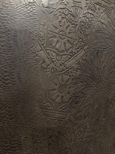 Muster aus dunklem Material mit floralen und geometrischen Motiven.