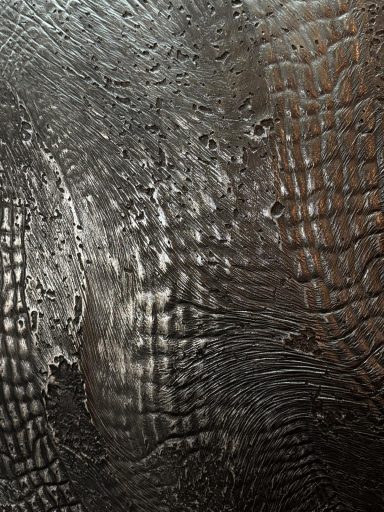 Texturierte Oberfläche in verschiedenen Grautönen mit schimmernden Linien und Mustern.